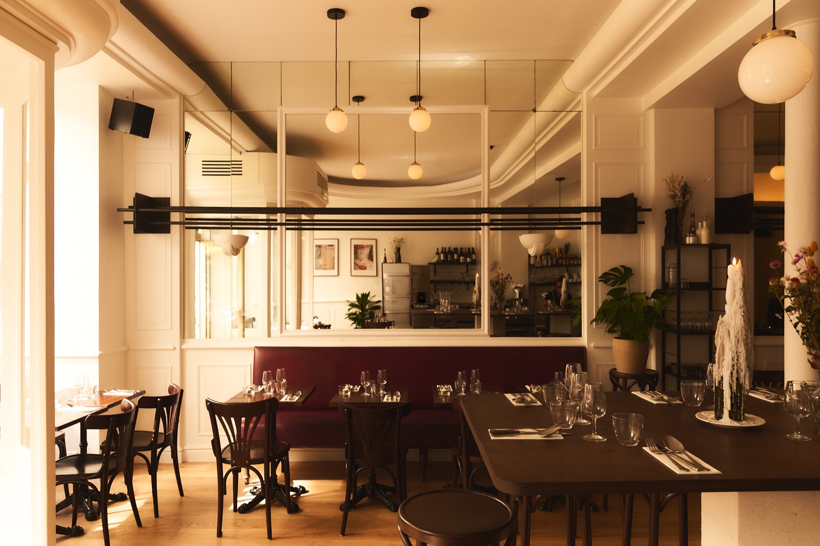 La salle de SUGO Osteria, banquette bordeaux et suspensions en verre